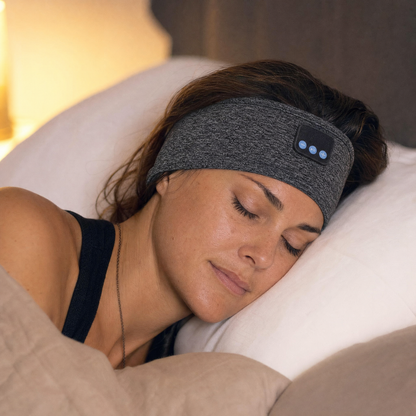 Woman asleep on her side in bed wearing the VESU Sleep Headband in Storm Grey, cheek resting on the pillow